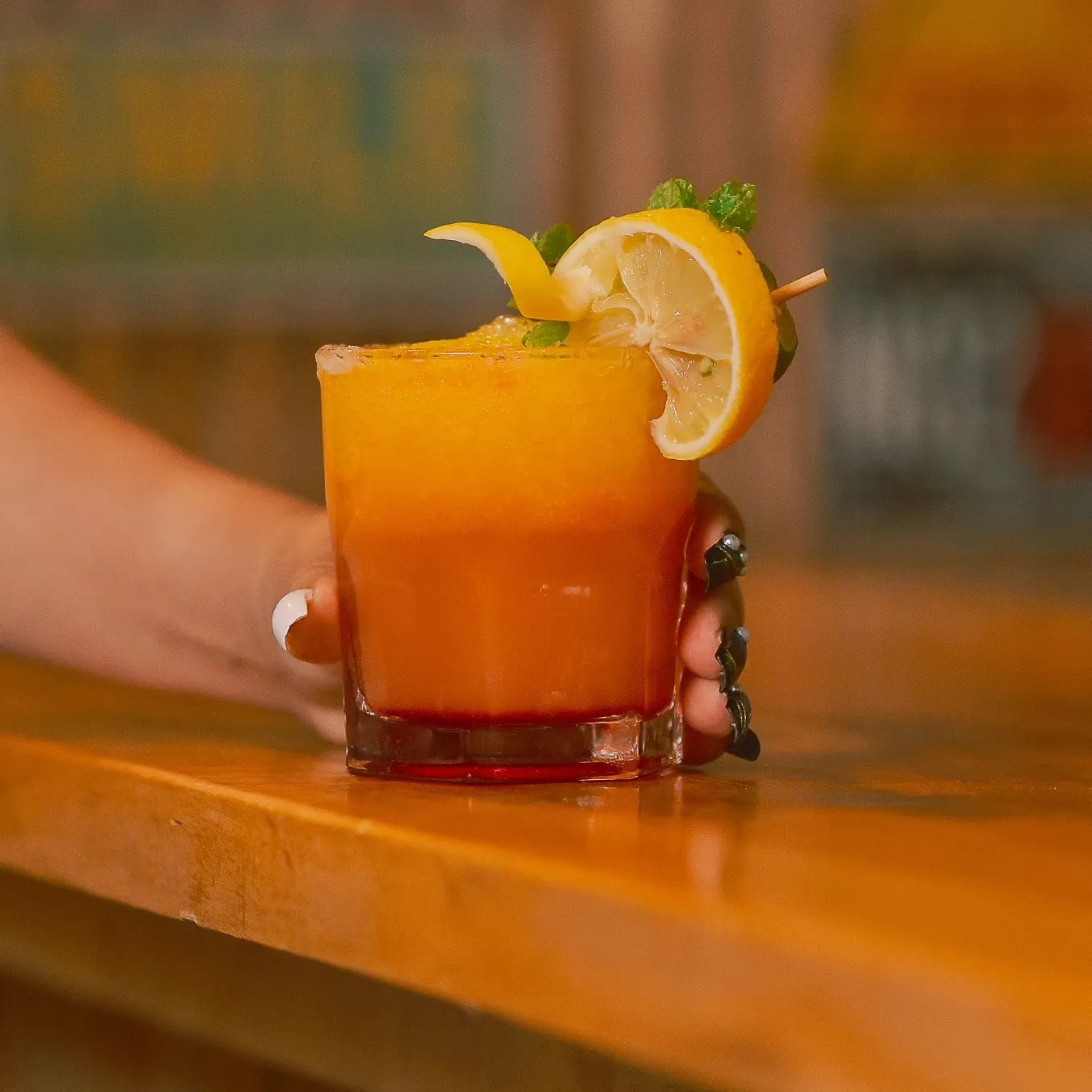 Sunrise-colored fruit cocktail garnished with lemon and mint at the beach bar of Patrick's on the Beach