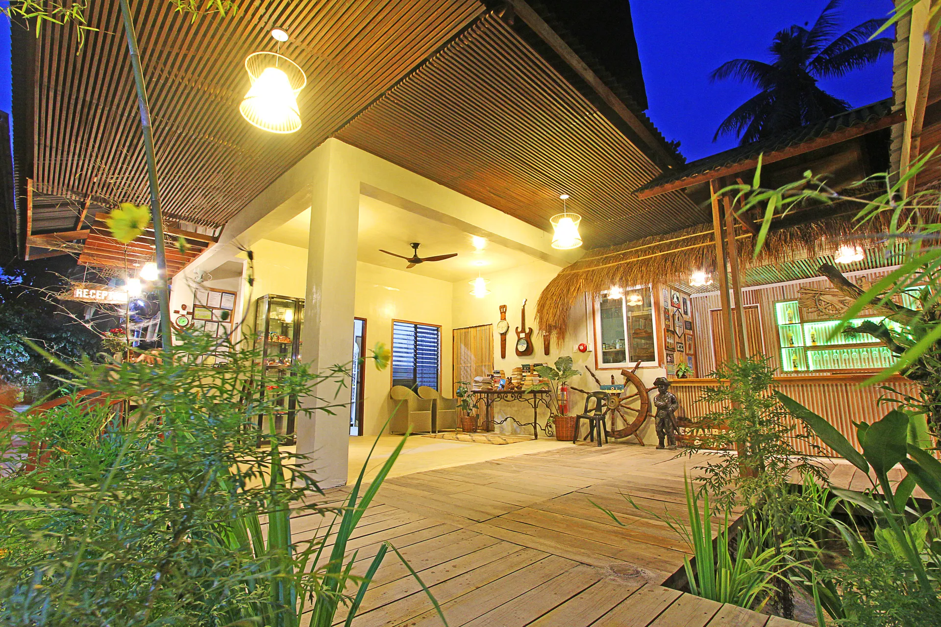 Warmly lit open-air reception deck at Patrick's on the Beach at dusk, surrounded by tropical plants