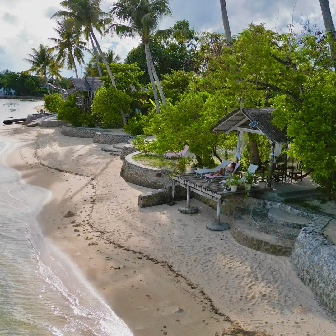 Aerial view of the beachfront, stone seawall and palm trees at Patrick's on the Beach, General Luna, Siargao